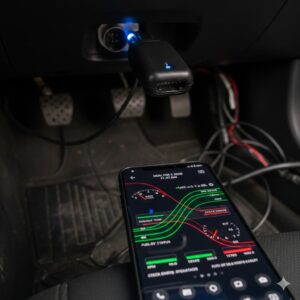 Primer plano de un escáner OBD2 conectado al puerto del coche con smartphone mostrando gráficos de diagnóstico en tiempo real