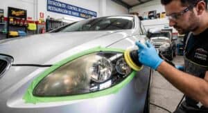 Técnico profesional puliendo un faro de coche amarillento y opaco para pasar la inspección ITV, mostrando el contraste antes y después.